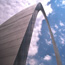 Looking up at the Gateway Arch with clouds in the sky.