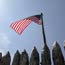 American flag waving over the top of the log wall of a replica of Camp Dubois.