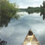 Silver tip of a canoe is in the foreground with the river and shoreline beyond Silver tip of a canoe is in the foreground with the river and shoreline beyond