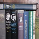 Books about Herbert Hoover stacked on a bookshelf.