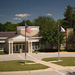 Two flags fly at the portico of a museum building.