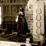 A blacksmith stokes the fire in a brick forge.