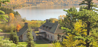 On a fall day filled with gold, orange and green vegetation; the depot overlooks a blue/gray Grand Portage Bay.