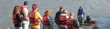 volunteers awaiting their ride to a site on the riverbank to pick up trash