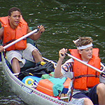 Two boys in a loaded canoe wearing lifejackets