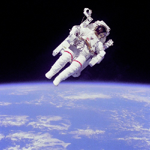 Astronaut floating in space with earth on the horizon.