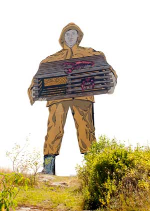 A display of a fisherman in a yellow slicker suit holding a lobster trap.