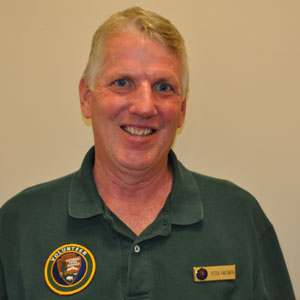 Photo of Peter Hacunda, NPS volunteer wearing dark green uniform shirt and volunteer patch.