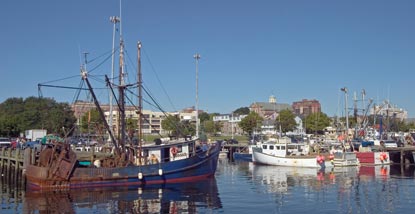 Fishing vessels in New Bedford harbor.  Buildings in New Bedford Whaling NHP can be seen in the background