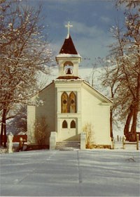 A white chapel during winter time with snow on the ground.