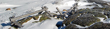 A wooden fence sits in the snow and ice.