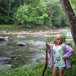 a young hiker stands by the river