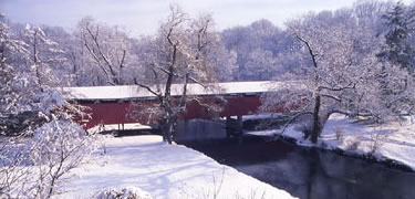 Red covered bridge across canal in snow