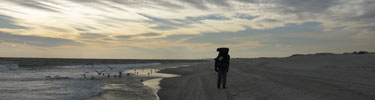 Backpacker hikes along winter beach.