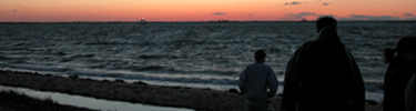 Group strolls down bayside beach into the setting sun.