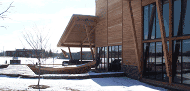 bright white snow & light reflecting into black pools of glass, a wooden building pops out from the crisp snowy surface