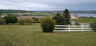 The scenic landscape includes two houses, a white fence, and the river.