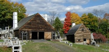 Weathered mill buildings are situated against a background of colorfull autimn trees.