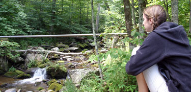 A young visitor sits by Rapidan River in historic Rapidan Camp.