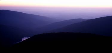 Darkened mountains meet purple skies in this photo of a sunrise.