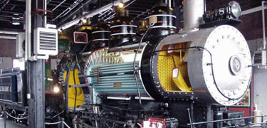 A steam locomotive with the side cut open shows uses colors to show the path of the steam, water and fire in a working engine.