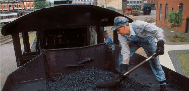 A fireman pushes the coal forward in the tender of a steam locomotive to make it easier to shovel. NPS Photo, Ken Ganz