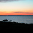 Small boat with raft attached, both anchored in bay during sunset.