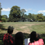 Small group gazes across large lawn to white manor house. Small group gazes across large lawn to white manor house.
