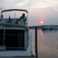 Couple watches view of sunset from aboard a large motor boat.