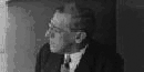 a man in black and white framed in his glasses looks into the distance