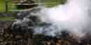Charcoal mound steaming and smoldering as it changes from wood into charcoal.