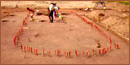 Markers in the ground in the oval shape of a  Native American longhouse