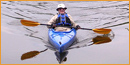 An older  man in a kayak on calm water