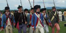 A very young man in a deep sky blue New Hampshire Regiment uniform coat leads several soldiers in a drill.
