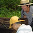 A ranger and a child make discoveries around an old fallen log in the forest.
