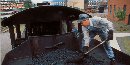 A fireman moves coal forward in the coal bunker of a steam locomotive to make the coal easier to use.