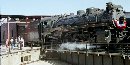 A steam locomotive rolls onto the turntable while visitors watch.
