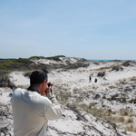 Hiker with friends in distant clearing behind the dunes.