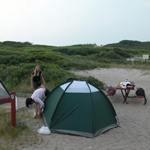 Campers set up tent in barrier island campsite.
