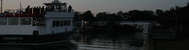 Ferry pulls up to dock with train cars in background.