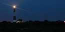 Flash atop black-and-white striped lighthouse tower at night. Flash atop black-and-white striped lighthouse tower at night.