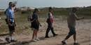 Group walks down the island behind the dunes. Group walks down the island behind the dunes.