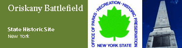 green maple leaf, symbol of NYS parks assoc. a tall white granite tower in front of a deep blue sky, Orskany Battlefield NYSHS