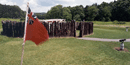 A red flag flutters a British flag; behind it stands a picket fence in a circle, there is a small entrance A red flag flutters a British flag; behind it stands a picket fence in a circle, there is a small entrance