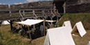 tents with white walls surround grass and wooden walls twice as tall