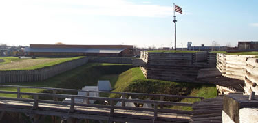 The southern walls and pickets and walls are lit up by sunlight, a historic flag flutters in the distance, as view from the eastern wall.