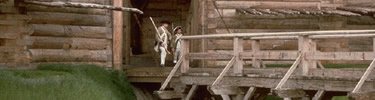 Soldiers in Continental uniform stand on guard duty, under the shadows of the front gate. Bridge streching over the ditch in front of them.
