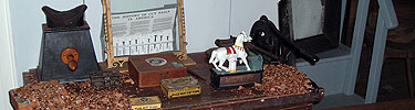 Assorted items--including a pony bank and historic boxes--sit on a table.