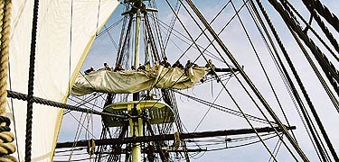 NPS volunteers and staff furl the mizzen topsail on <i>Friendship</i>. NPS photo.