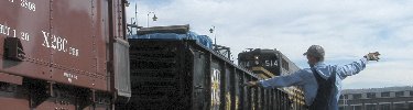 One of Steamtown's volunteers signals the engineer to stop as a gondola and caboose are coupled.  NPS Photo, Ken Ganz